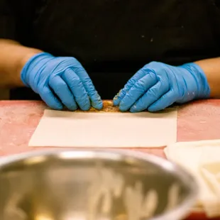 a person in a black shirt and blue gloves preparing food