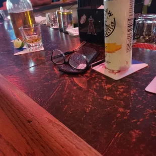 a can of beer and a cell phone on a bar
