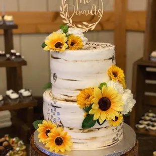 a three tiered cake with sunflowers