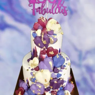 a three tiered cake with purple and gold decorations