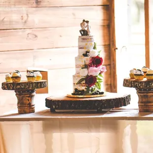 a three tiered wedding cake and cupcakes