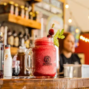 a red drink with a straw and garnish