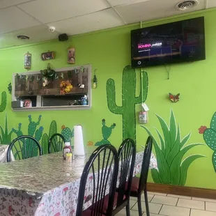a dining room with a cactus mural on the wall