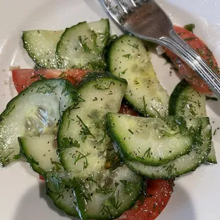 a plate of sliced cucumbers and tomatoes