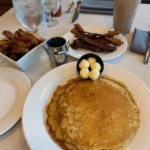 a plate of pancakes with butter and bacon