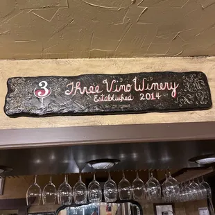 a sign above a bar with wine glasses