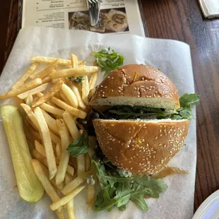 Fantastic French Fries and Meister burger with blue cheese and Arugula spilling out tantalizingly with a side of pickled cucumber