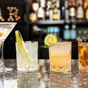 three different cocktails on a bar