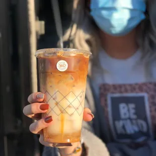 a woman wearing a face mask and holding a cold drink