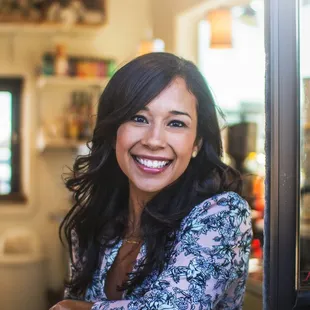 a woman smiling and leaning against a window