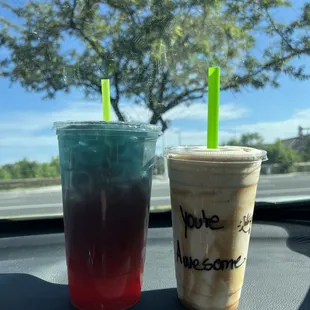 two drinks on the dashboard of a car