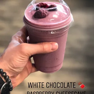 a hand holding a cup of raspberry cheesecake smoothie