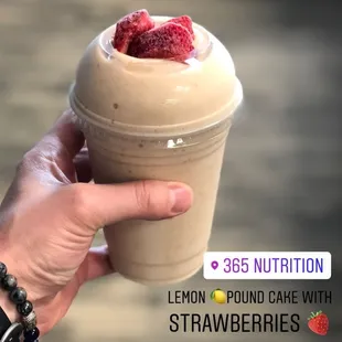 a hand holding a cup of strawberries