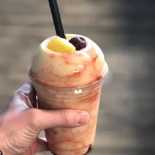 a hand holding a cup of fruit smoothie
