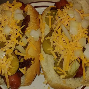 two hot dogs covered in cheese and onions