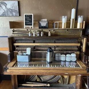 Old school piano where the creamer, spices and sweeteners are located.
