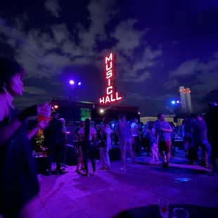 a crowd of people standing in front of a neon sign