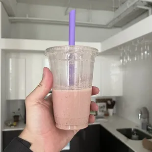 a hand holding a plastic cup with a purple straw