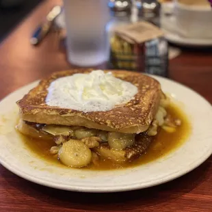 a plate of french toast with bananas and cream