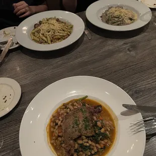 Duck confit in foreground, sausage pasta and risotto in background