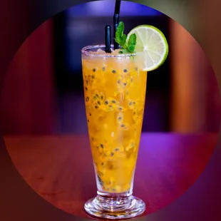 a glass of orange juice with a slice of lime