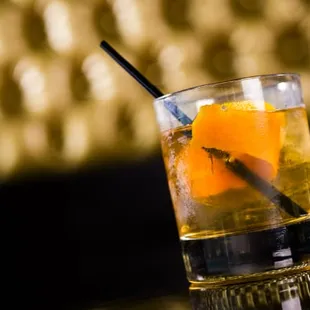 a glass of alcohol with an orange slice in it