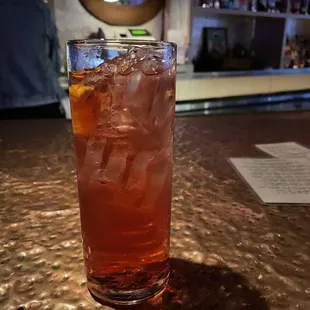 a tall glass of iced tea on a bar