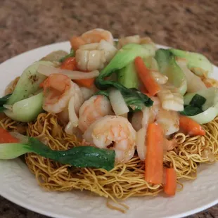 a plate of noodles with shrimp and vegetables
