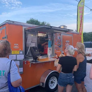 a group of people standing in front of a food truck