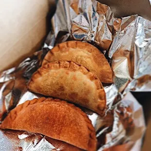 three empanadas wrapped in aluminum foil