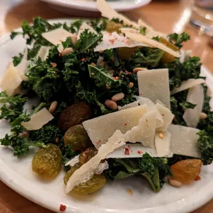 Kale Salad. Large $10. Pictured here is 1/2 serving. Pine nuts, golden raisins, shaved Parmesan, chili flakes, citrus vinaigrette.