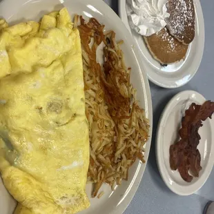 Egg omelette, hash browns, bacon strips, and chocolate chip pancakes.