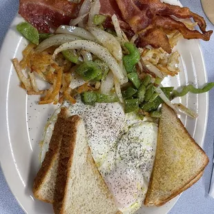 a plate of food with toast, eggs, bacon, and onions