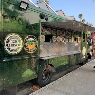 a green food truck parked on the side of the road