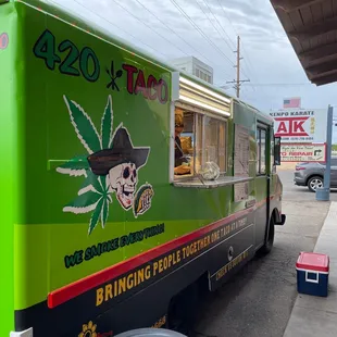 a green food truck parked on the side of the road