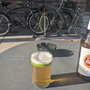 a glass of beer on a table with bicycles in the background