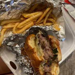 a sandwich and french fries in a styrofoam container