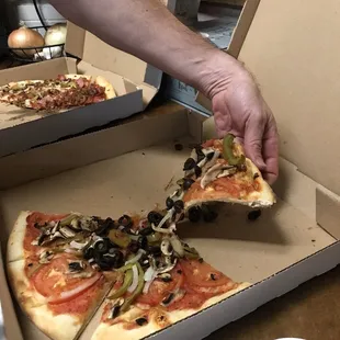 a person taking a slice of pizza