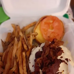 a burger and fries in a styrofoam container