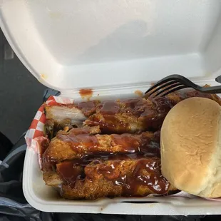 a chicken sandwich and a roll in a styrofoam container