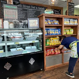 a woman picking up a bag of chips