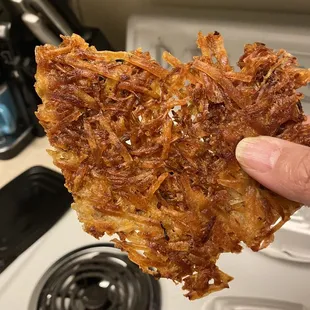 a hand holding a piece of fried food