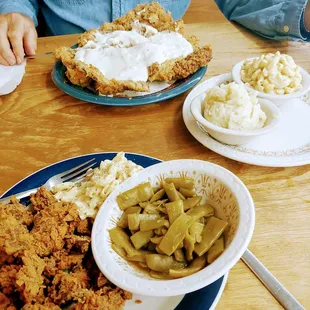a plate of fried chicken, a bowl of green beans, and a bowl of mashed potatoes