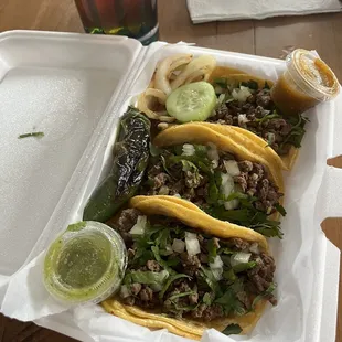 three tacos in a styrofoam container