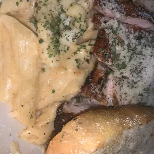 a plate of meat, pasta, and bread
