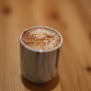 a cup of cappuccino on a wooden table
