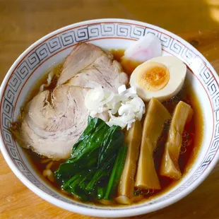 a bowl of ramen with meat, eggs, and broccoli