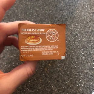 a hand holding a breakfast syrup bar