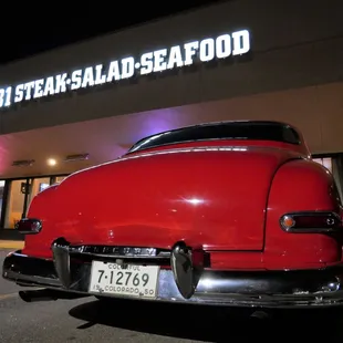 a red car parked in front of a restaurant