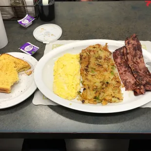 a plate of eggs, bacon, hash browns and toast